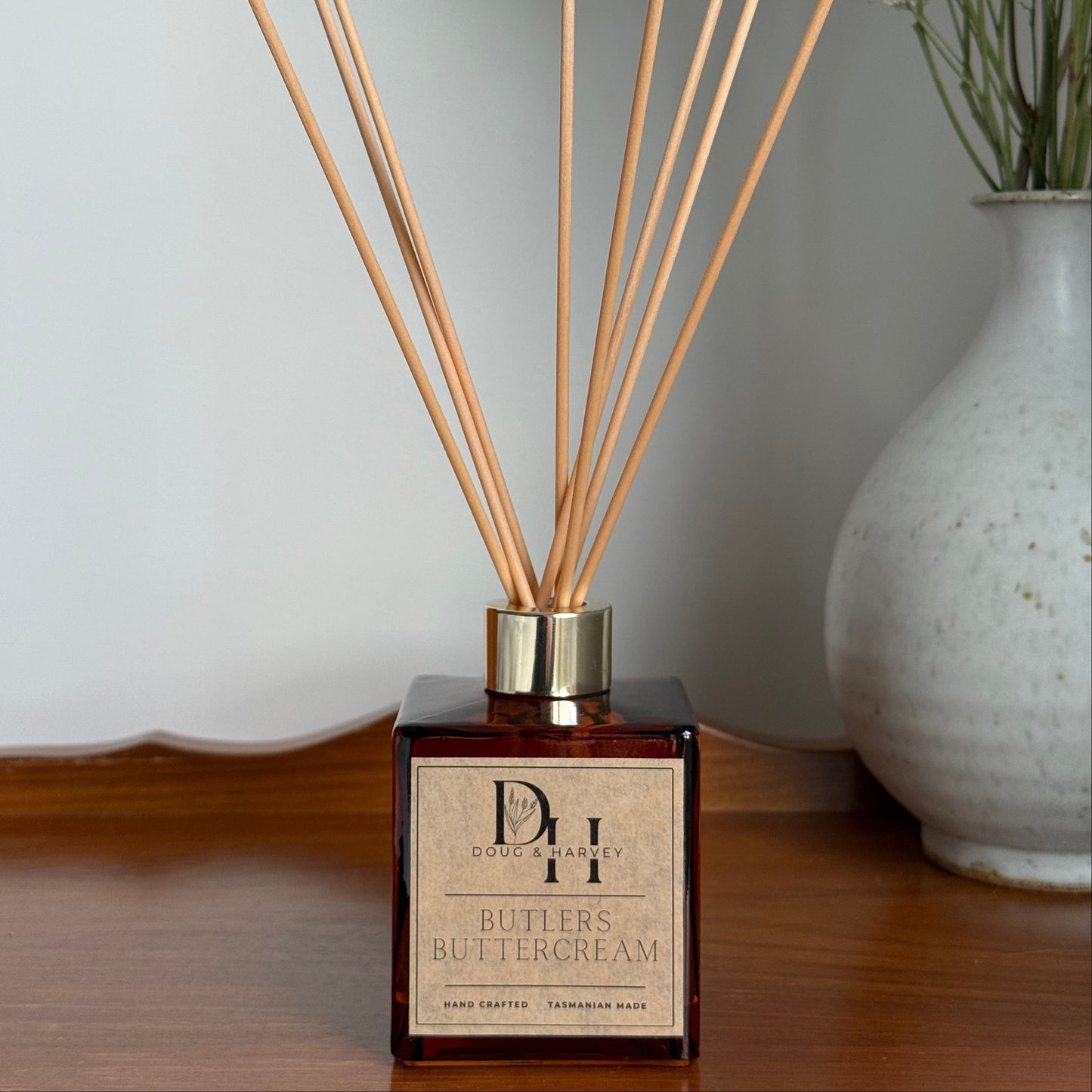 Diffuser with reeds and a decorative vase on a white surface
