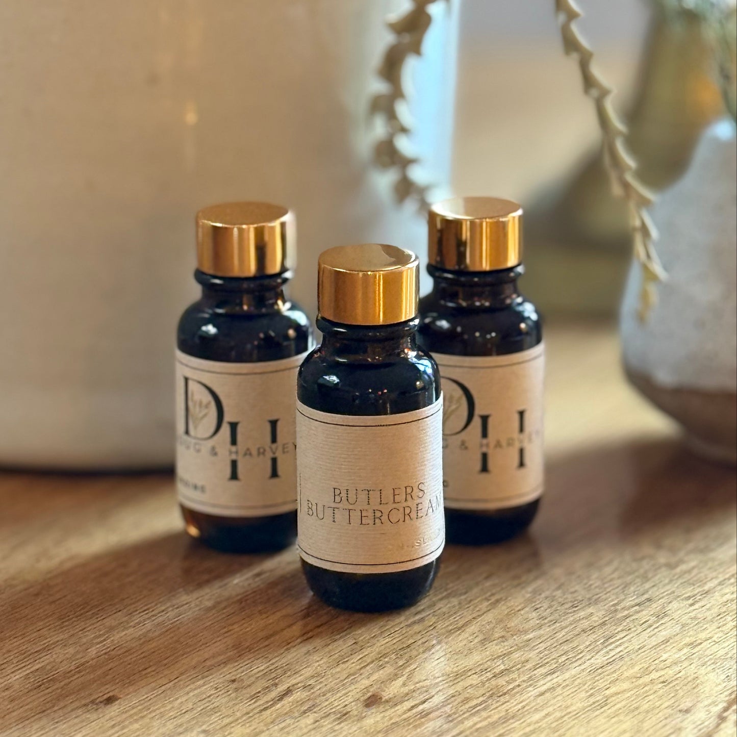 Three small bottles of diffuser oil with gold caps and labels on a wooden surface.