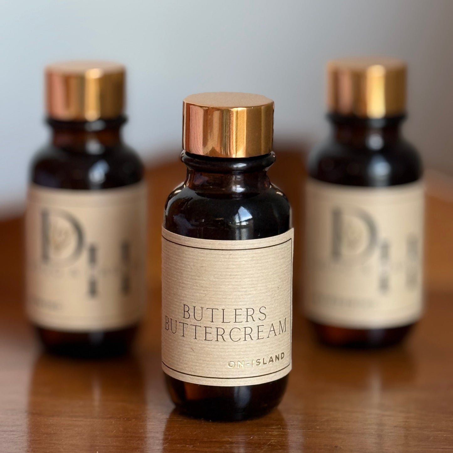 Three bottles of Butlers Buttercream diffuser oil on a wooden surface with a neutral background