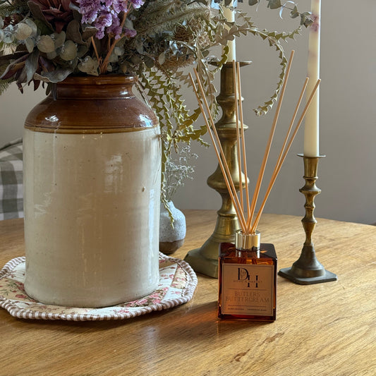 Decorative candle holder with flowers and a bottle on a wooden surface