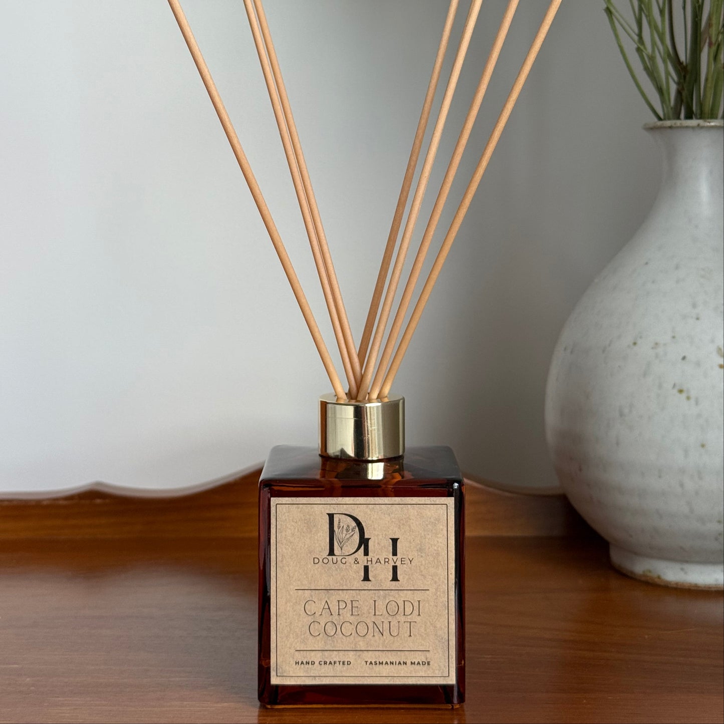 Diffuser with wooden sticks and decorative vase on a light surface
