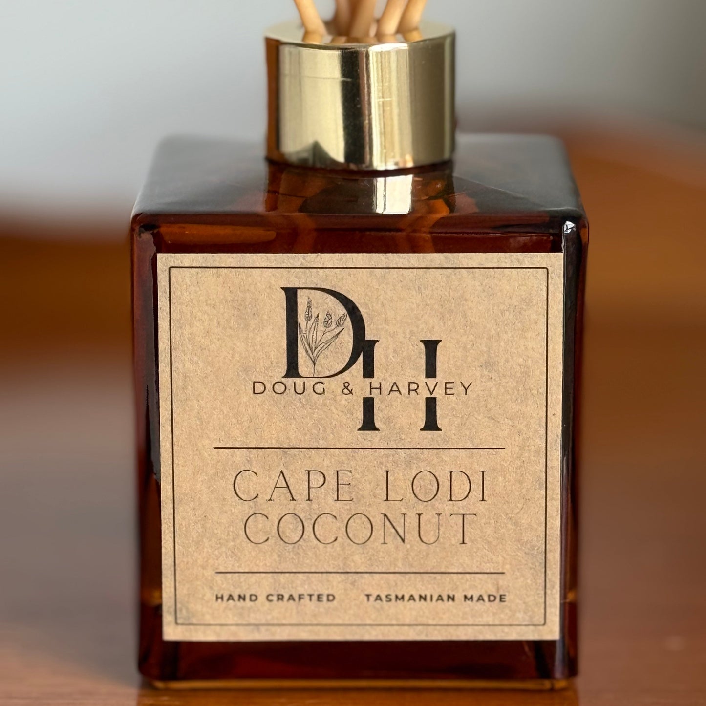Reed diffuser bottle labeled 'Cape Lodi Coconut' by Doug & Harvey on a wooden surface.