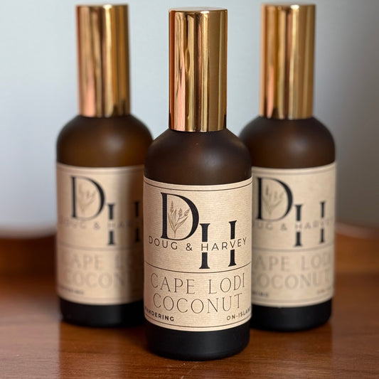 Three bottles of Doug & Harvey Cape Lodi Coconut on a wooden surface with a light gray background