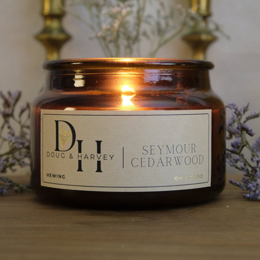 Candle in a brown jar with a label on a wooden surface