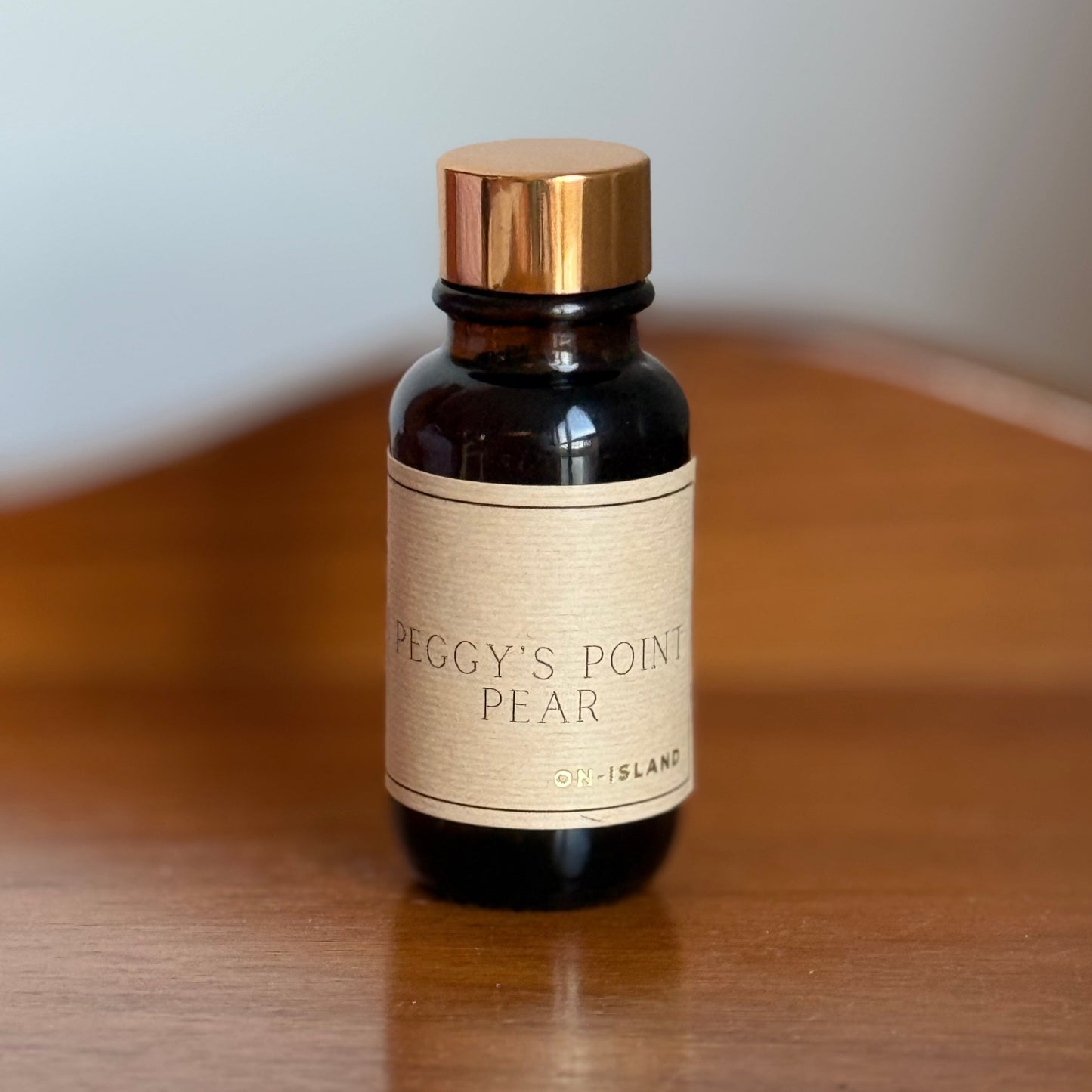 Small bottle with a gold cap and beige label on a wooden surface