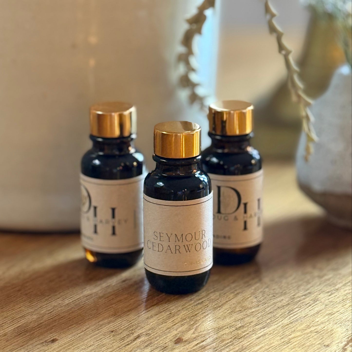 Three small bottles with gold caps on a wooden surface, with a blurred background.