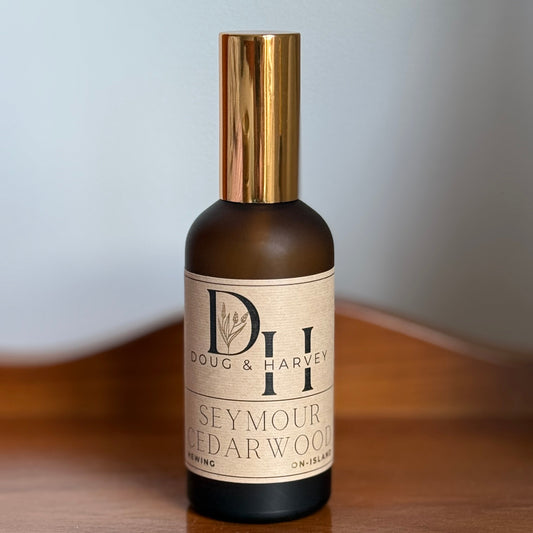 Bottle of Doug & Harvey Seymour Cedarwood on a wooden surface with a light gray background