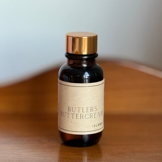 Bottle of Butler's Buttercream diffuser oil on a wooden surface with a white background