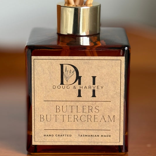 Reed diffuser bottle labeled 'Butlers Buttercream' by Doug & Harvey on a wooden surface.