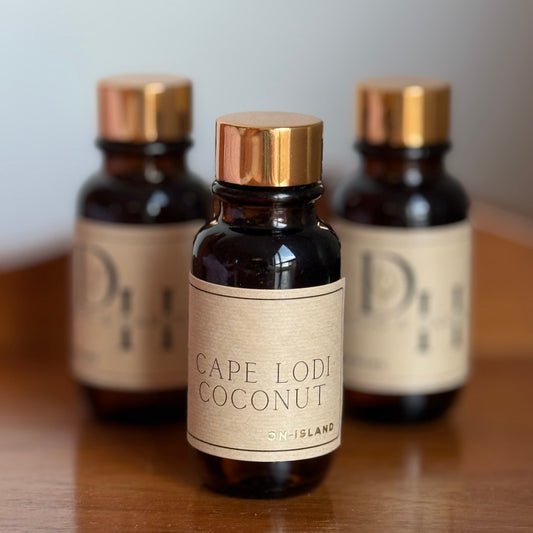 Three bottles of Cape Lodi Coconut on a wooden surface with a neutral background