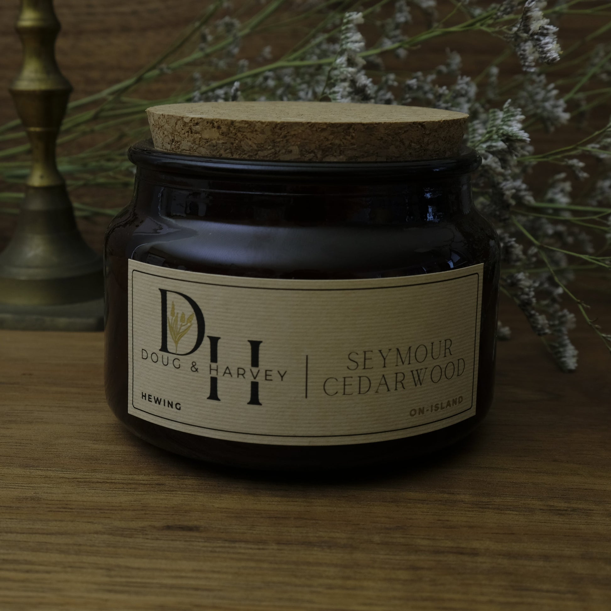 Jar of candle with a cork lid on a wooden surface with decorative elements.
