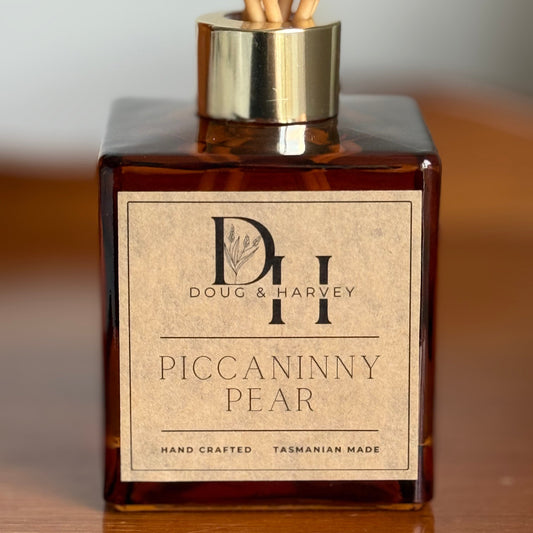 Diffuser bottle labeled 'Piccaninny Pear' by Doug & Harvey on a wooden surface.
