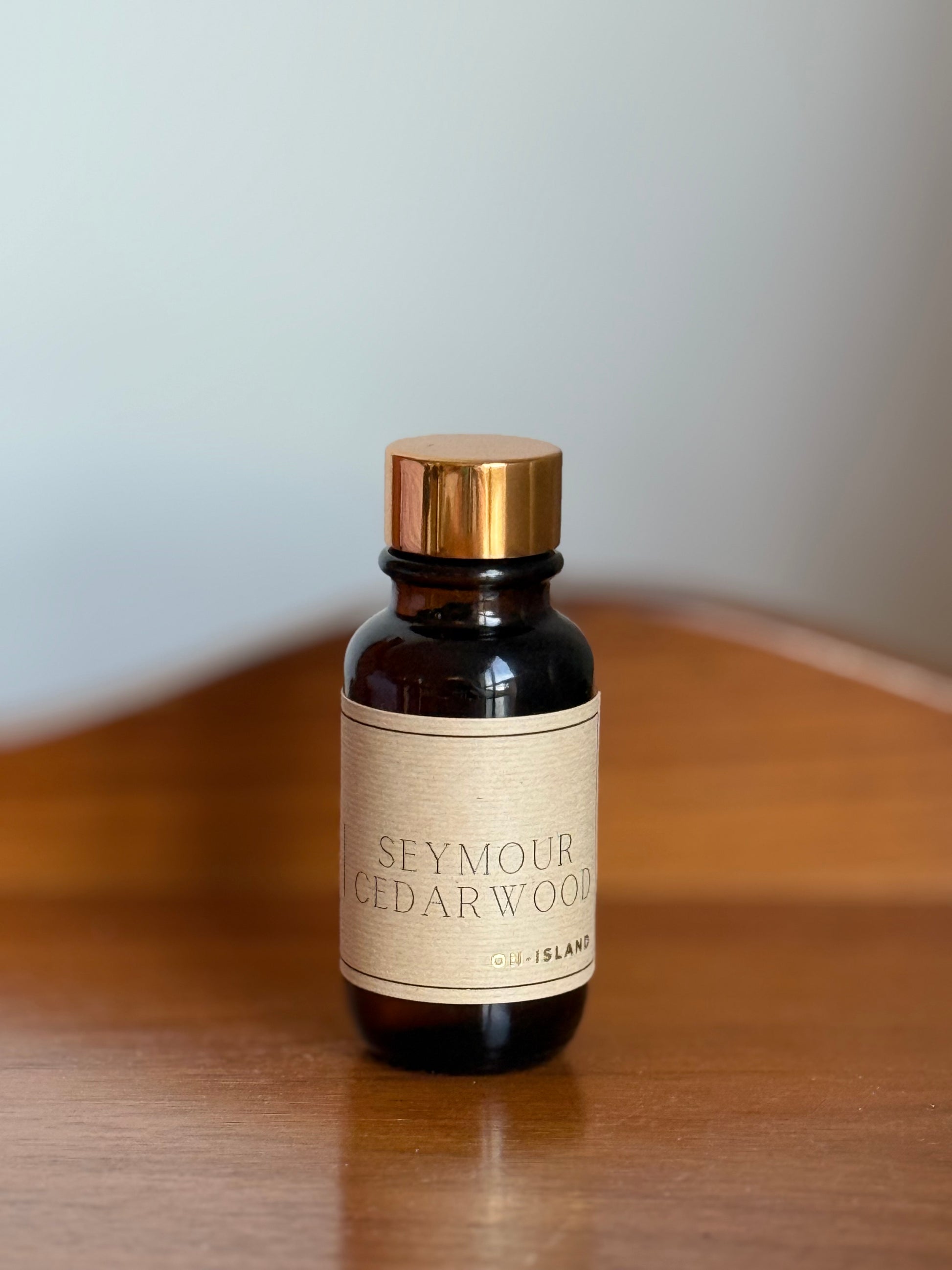 Bottle of Seymour Cedarwood oil on a wooden surface with a neutral background