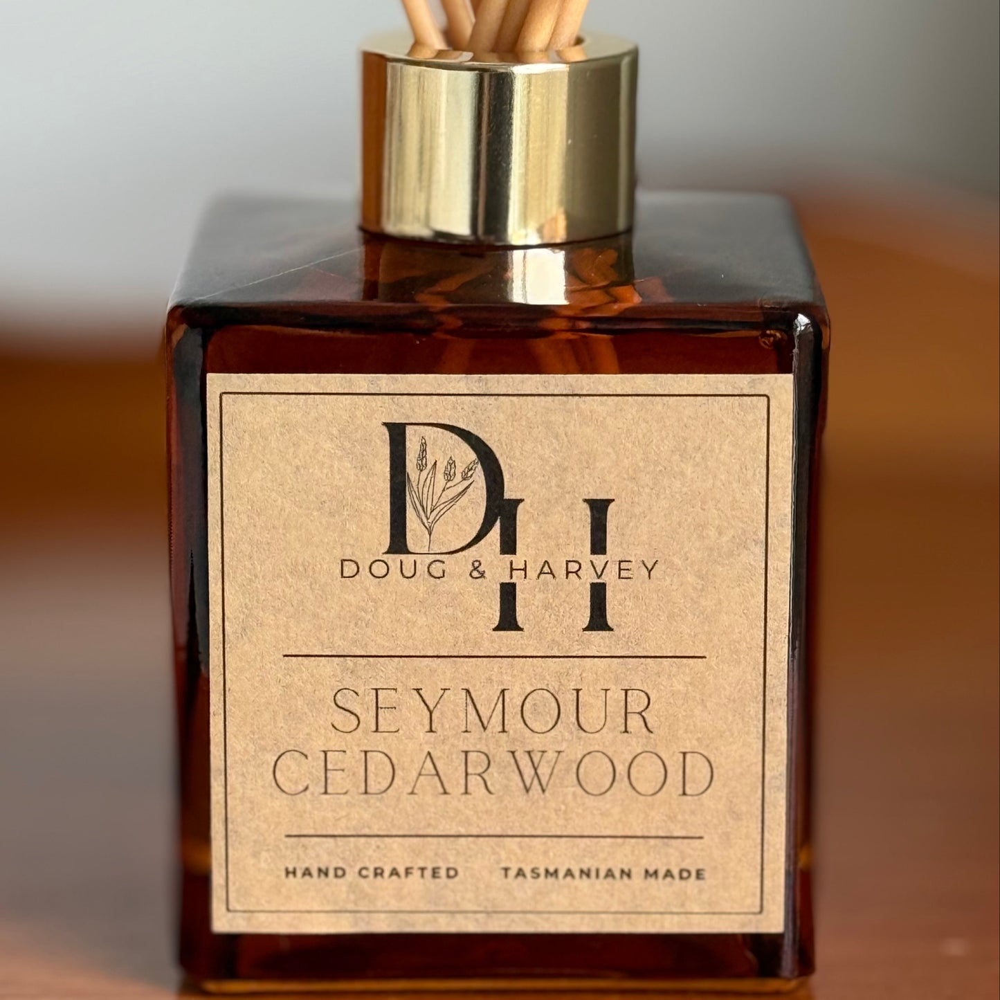 Diffuser bottle with wooden sticks labeled 'Doug & Harvey Seymour Cedarwood' on a wooden surface.