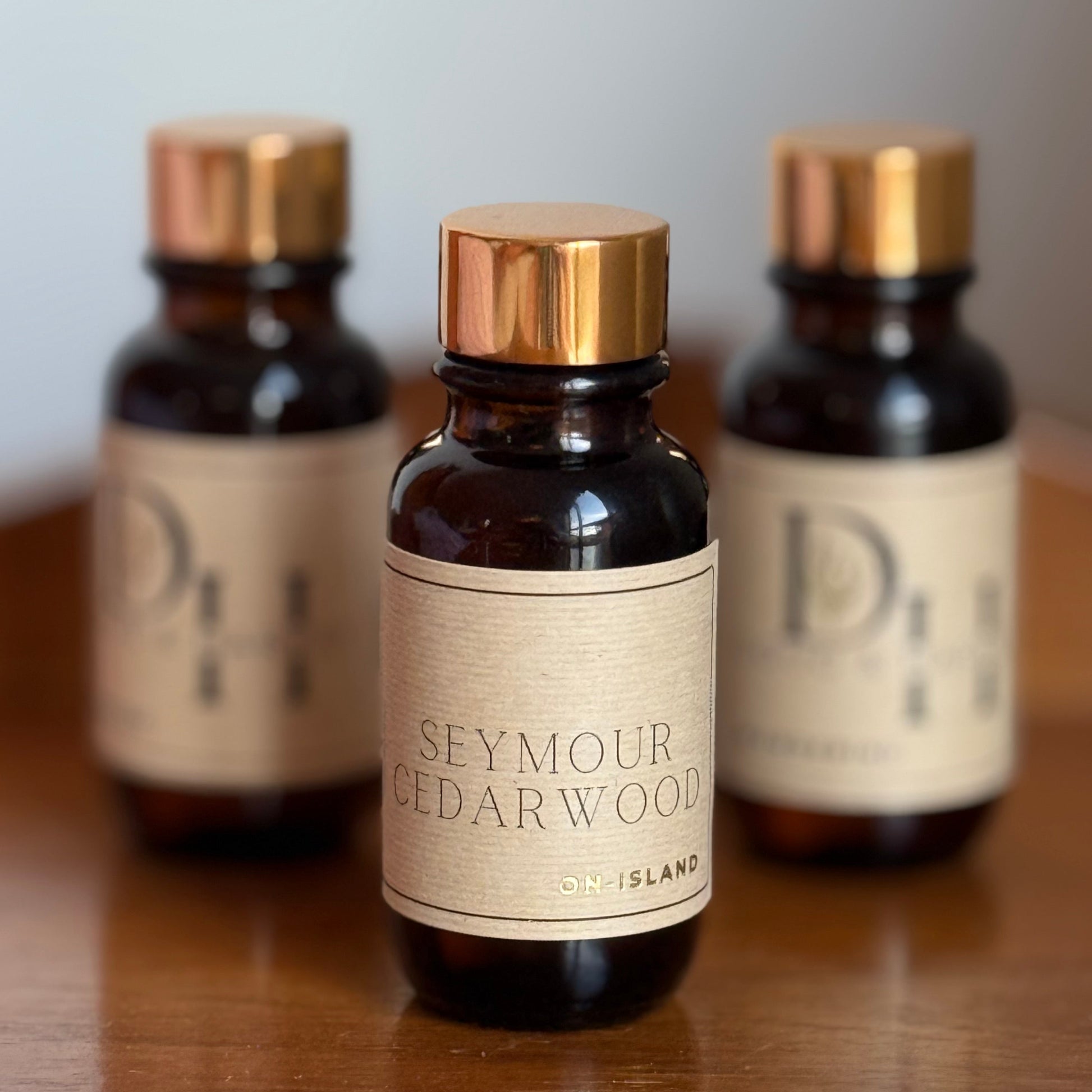 Three bottles of 'Seymour Cedarwood' on a wooden surface with a neutral background
