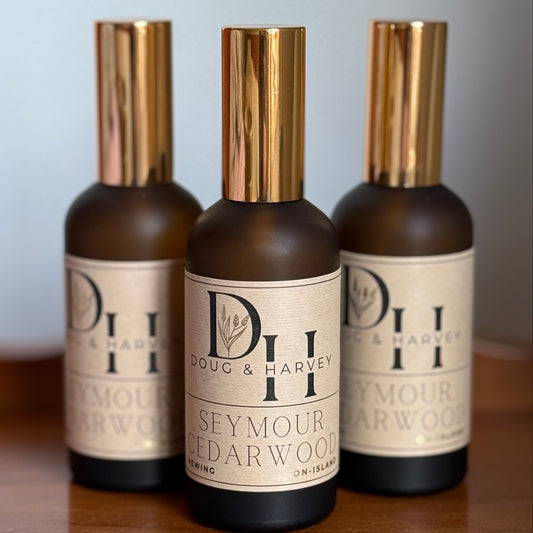 Three bottles of Doug & Harvey Seymour Cedarwood on a wooden surface with a light gray background
