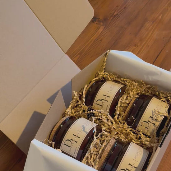 Doug & Harvey luxury amber glass candle jars and cork lid match jars packed in a gift box with natural crinkle paper on a timber table, styled in a warm Tasmanian country aesthetic.