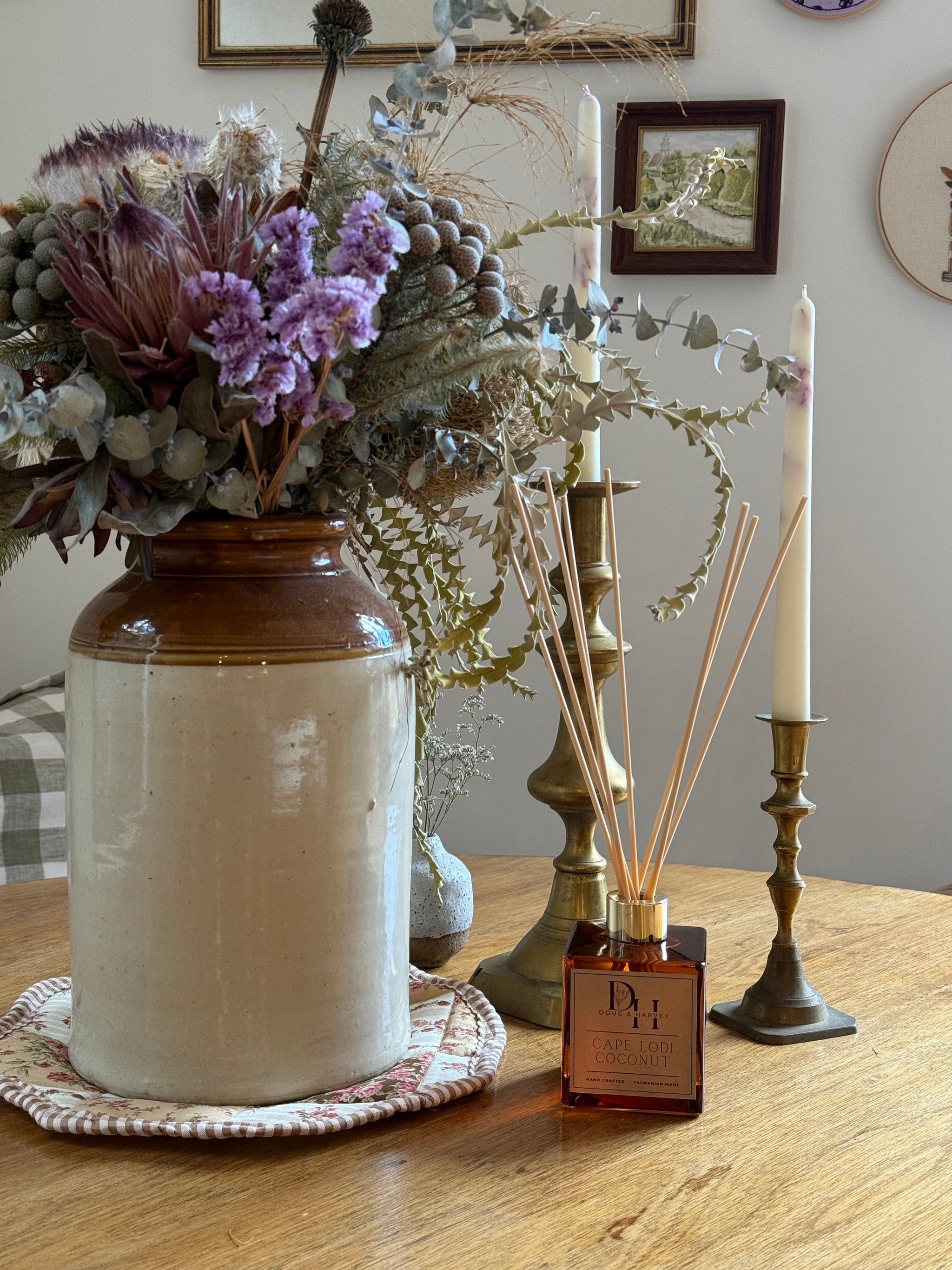 Cape Lodi Coconut Natural Reed Diffuser inserting rattan reeds into square diffuser on country table